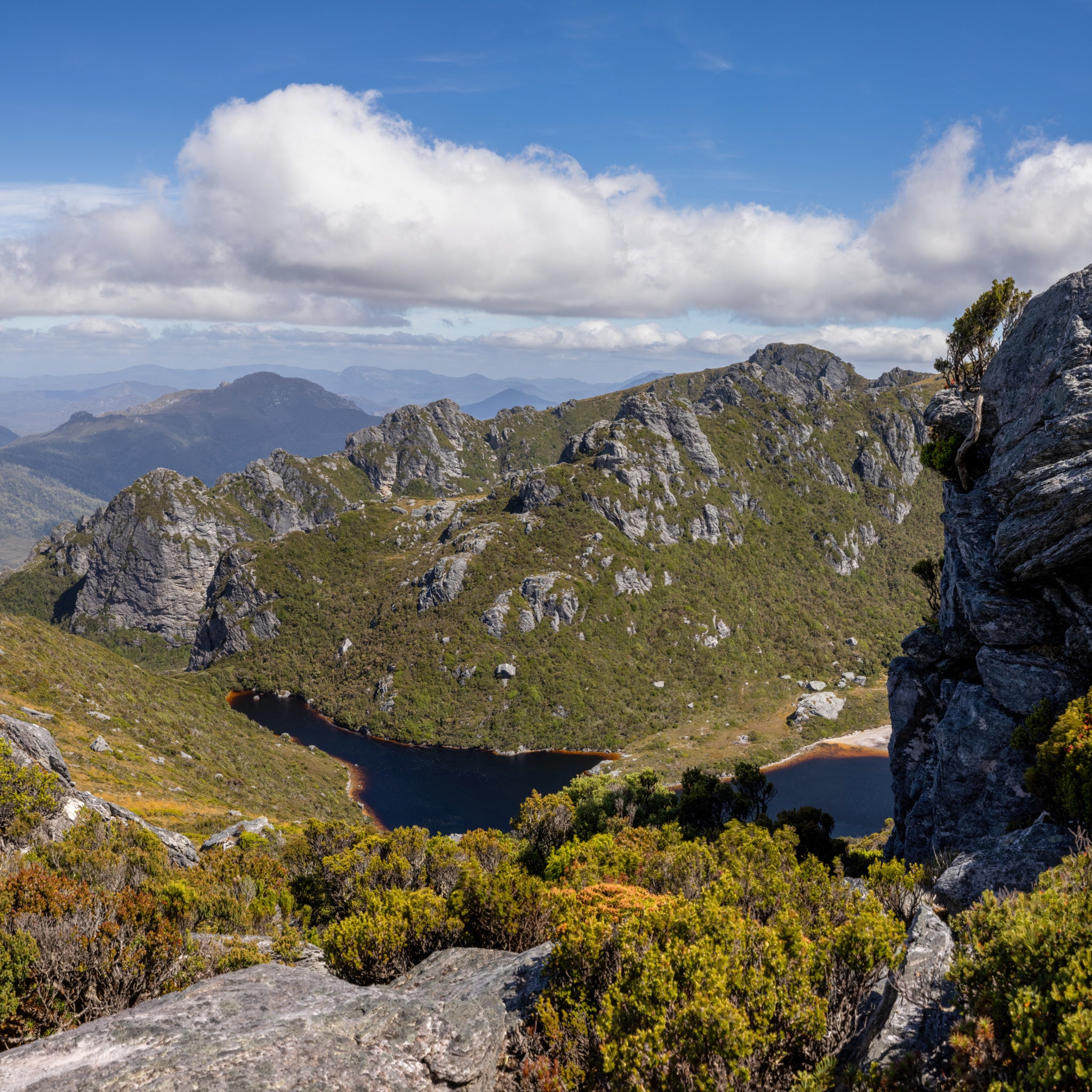Peeping around a rock at the top of the corrie wall to catch a glimpse of Lake Cygnus below. Taken on a beautiful morning at the top of the Western Arthurs in Tasmania, Australia