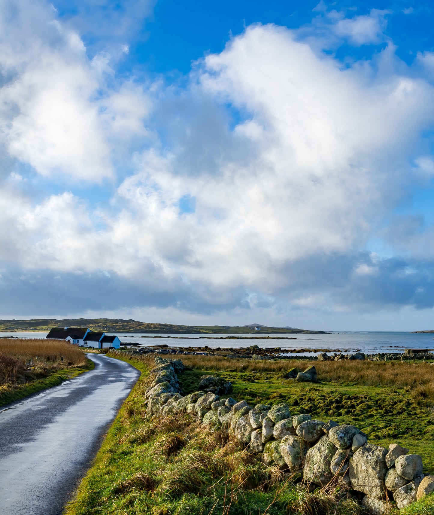 A quiet Irish cottage beside the sea with soft Connemara clouds over a shining sea.   My brother dropped me by the side of the road while he went to get some salmon - the light ebbed and flowed but I caught this moment for posterity.  Taken on a beautiful winter's morning at Claddaghduff near Galway. Ireland at its best.