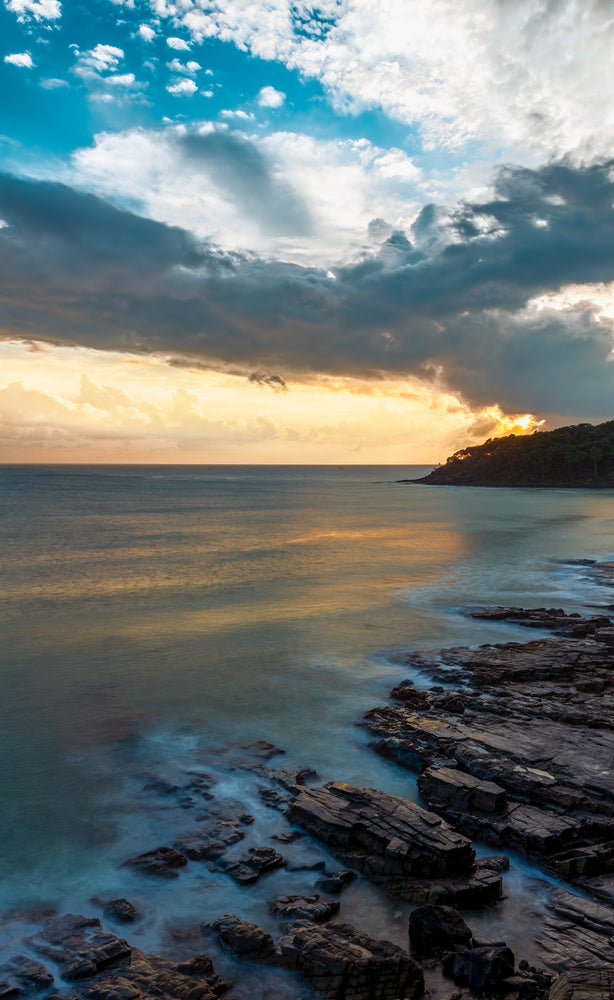 Golden morning light reflecting off a smooth sea along the Hellsgate path near Noosa in Queensland, Australia.