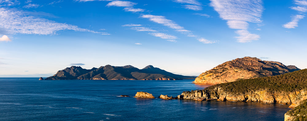 Early morning light breaks through cloud and illuminates Cape Tourville at Freycenet in Tasmania, Australia.