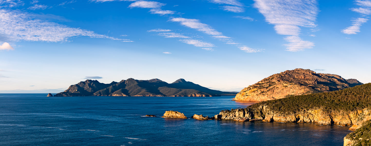 Early morning light breaks through cloud and illuminates Cape Tourville at Freycenet in Tasmania, Australia.