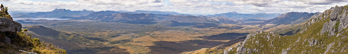 A huge panaorama overlooking Scott's Peak Dam and the Junction Creek valley. The valley floor is filled with light and shadow from the clouds scudding across the sky. Taken from atop the Western Arthurs in Tasmania, Australia.